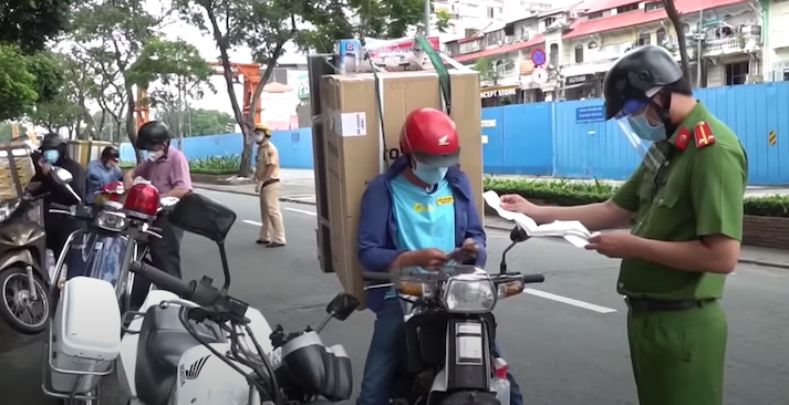 Lực lượng chức năng kiểm tra các shipper trên đường (ảnh chụp màn hình video Tuổi Trẻ đăng trên Youtube). Giới chức TP.HCM đang xem xét cho người dân tự đặt hàng, giao nhận hàng qua shipper để giảm tải cho hệ thống "đi chợ giúp dân".