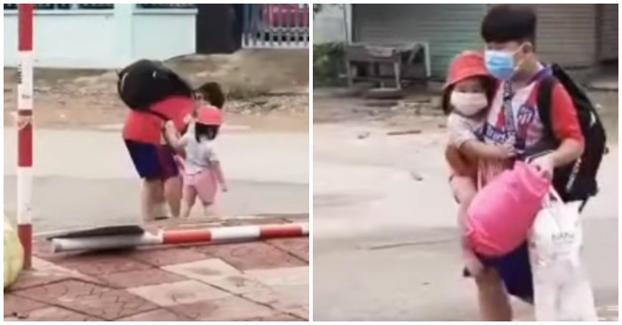 Cậu bé xách nhiều đồ nặng, tay còn lại cố gắng bế em nhỏ (ảnh cắt từ clip).